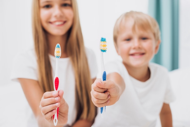 Foto fratelli germani che mostrano i loro spazzolini da denti