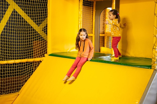 Siblings sliding at yellow playground park Sisters in active entertaiments