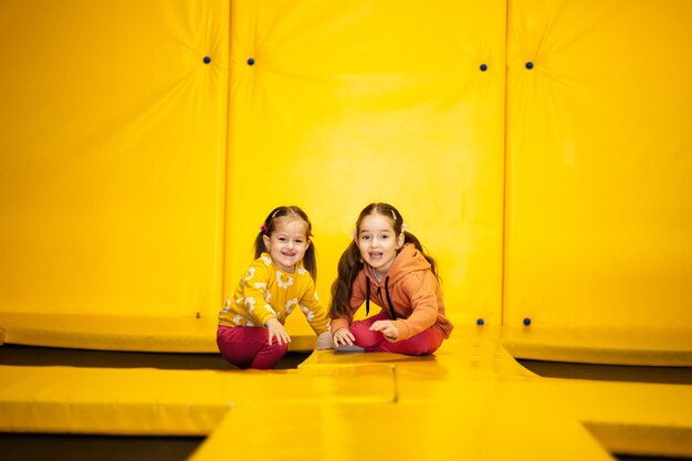 Siblings on trampoline at yellow playground park sisters during active entertaiments