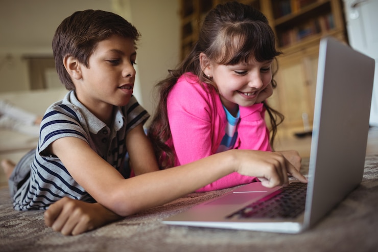 Photo siblings using laptop in living room