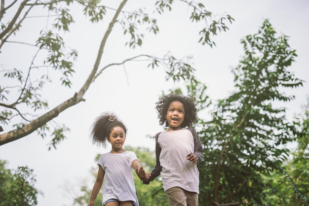 Photo siblings walking against trees