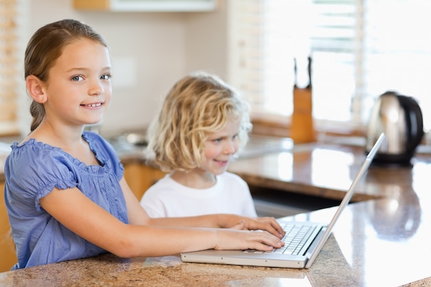 Siblings with laptop behind the kitchen counter