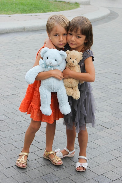 Siblings with teddy bears standing on footpath