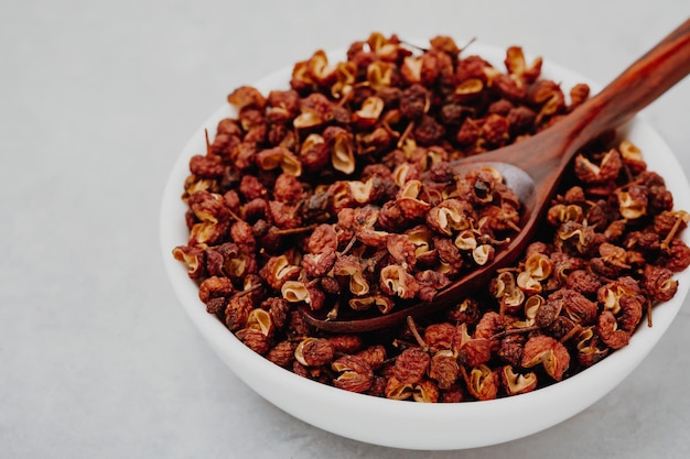 Sichuan pepper Chinese pepper Zanthoxylum schinifolium in bowl on gray stone background closeup