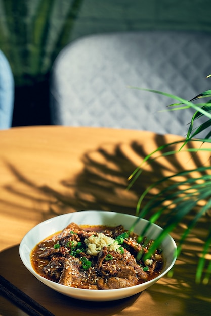 Sichuan spicy beef in a spicy sauce, garlic, pepper, sesame seeds in a white bowl. Chinese cuisine. shuizhu, shui zhu