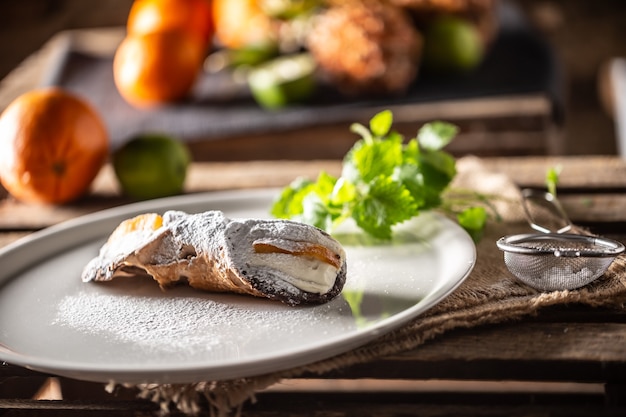 설탕을 얹은 시칠리아 카놀리(Sicilian Cannoli) 달콤한 디저트가 접시에 제공됩니다.