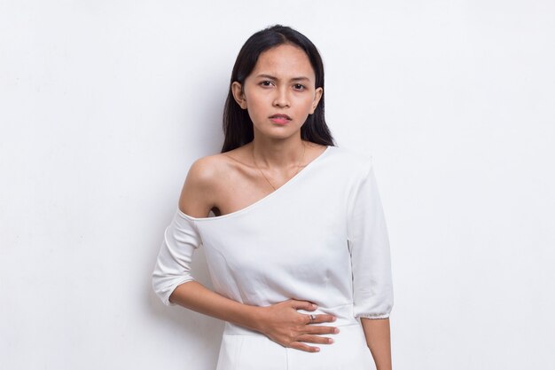 Больной азиатской красивой молодой женщины, имеющей боль в животе, изолированную на белом фоне