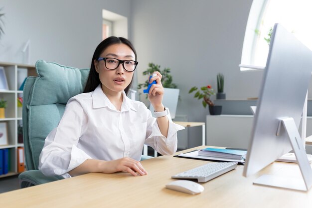 사무실에서 일하는 아픈 아시아 비즈니스 여성은 흡입기를 사용하여 호흡 천식을 완화합니다