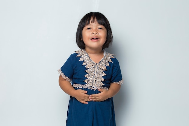 Больная азиатская маленькая девочка с болью в животе, изолированной на белом фоне
