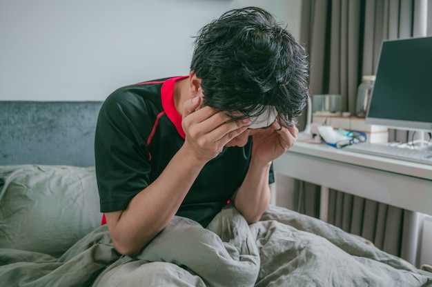 Sick asian man are headaches and use his hands to hold head