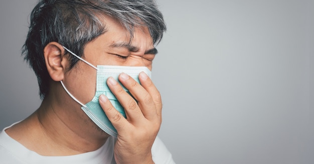 Sick Asian man wearing a medical face mask and Coughing and covering his mouth with my hand. Concept of protection pandemic coronavirus and respiratory disease