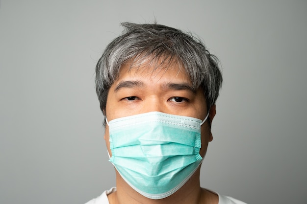 Больной азиатский мужчина, носящий медицинскую маску и боль в плече и стресс. Концепция защиты от пандемии коронавируса и респираторных заболеваний