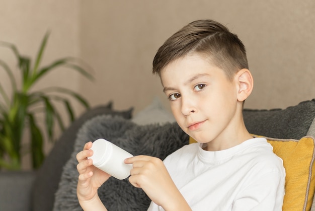 Sick Boy sits on the couch and looks at a jar with pills in his hands.