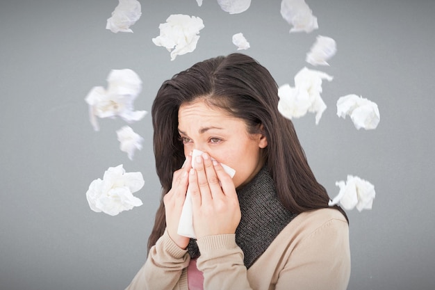 写真 灰色の背景に対して彼女の鼻をかむ病気のブルネット