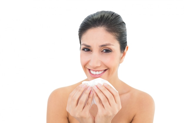 Sick brunette holding a tissue and smiling at camera