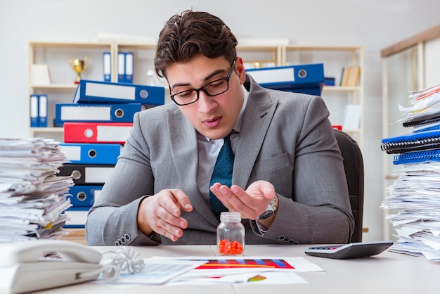 sick businessman with medicines at work desk