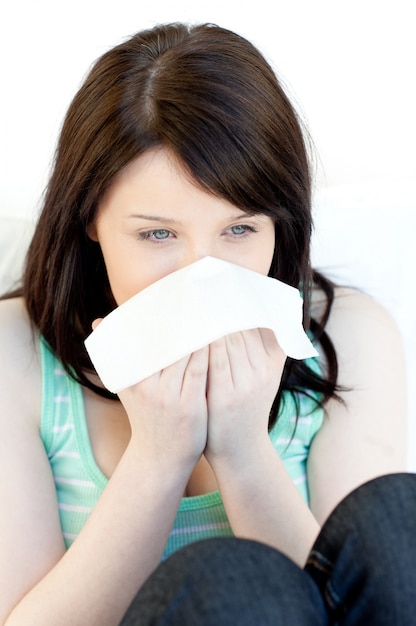 Sick charming woman blowing sitting on a sofa