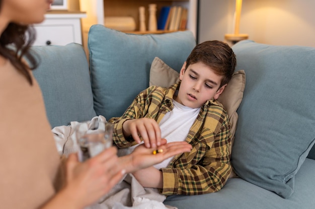 Photo sick child taking medicine tablet flu treatment and cold cure for illness sickness and virus symptoms mom caring for health of little son kid and boy to rest recover and get better in bed at home