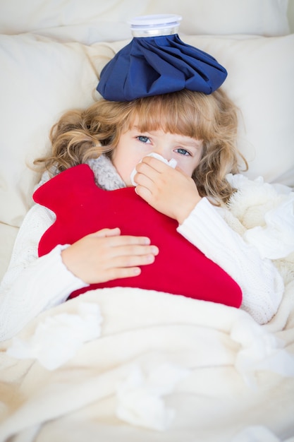 Photo sick child with fever and hot water bottle at home