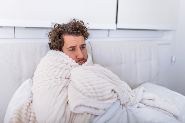 Sick day at home. Handsome Man has fever and common cold. Cough. Closeup Of Young Man Caught Cold Or Flu Illness. Portrait Of Unhealthy man Feeling Pain In Throat.