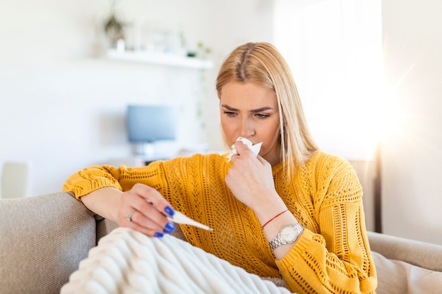 La donna malata disperata ha il coronavirus. covid 19, raffreddore, malattia, concetto di allergia. una donna abbastanza malata ha il naso che cola, si strofina il naso con il fazzoletto e guarda la temperatura sul termometro