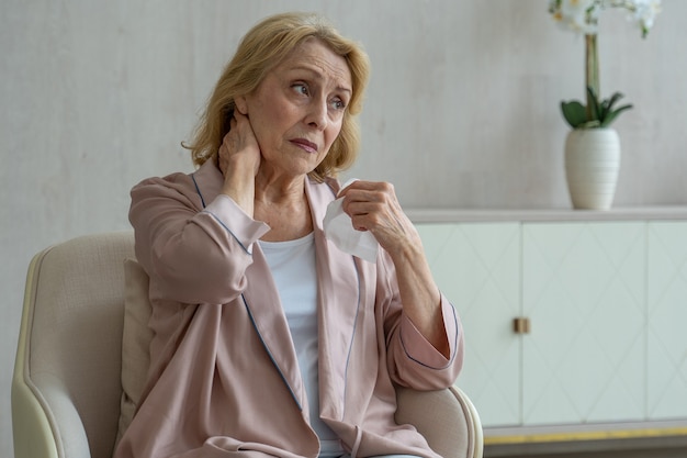 Foto una donna anziana malata starnutisce usando un tovagliolo di carta per il naso ha il naso che cola e tossisce