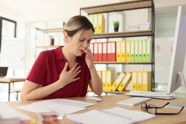 La manager donna malata tossisce mettendo la mano sul petto in ufficio