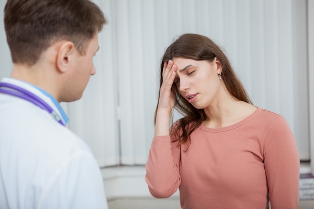 Sick female patient with migraine on medical appointment