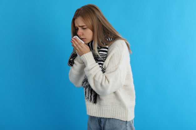 Sick girl on blue background, seasonal cold concept