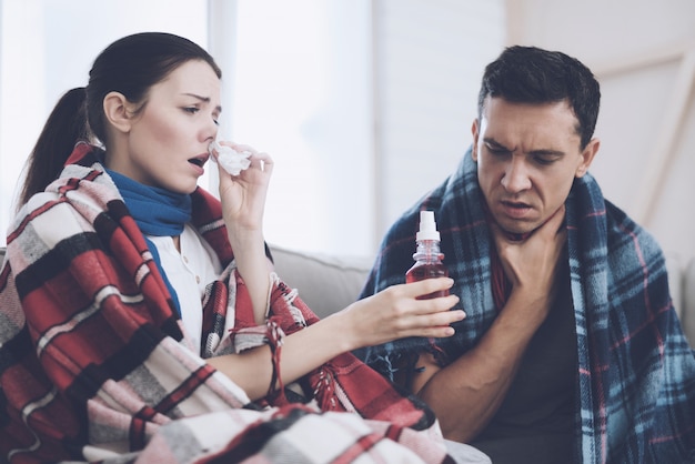 Sick girl dripping nose and handing drops to her husband.