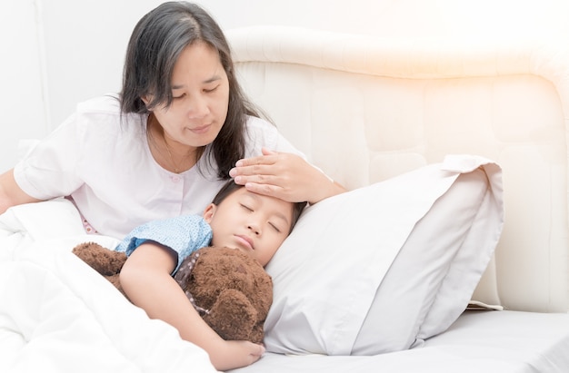 Sick girl laying in bed and mother hand taking temperature. 