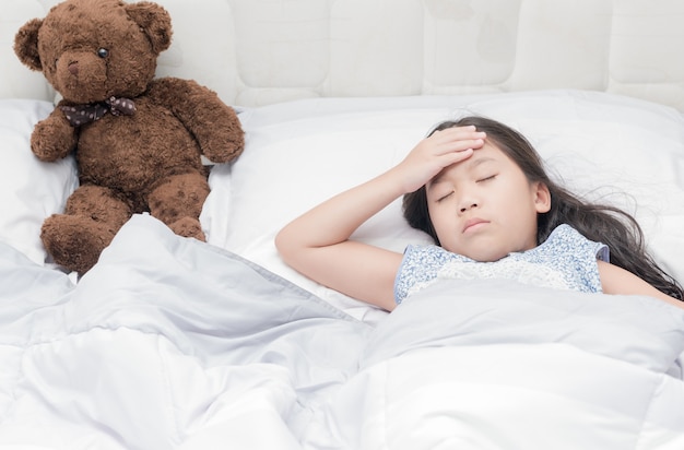 sick girl lying in bed and touch her forehead