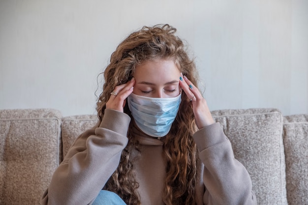 Photo sick girl in medical mask with headache symptom. coronavirus concept.