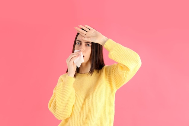 Ragazza malata con un maglione giallo su sfondo rosa