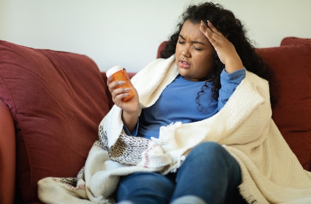 Sick hispanic chubby woman taking pill home interior