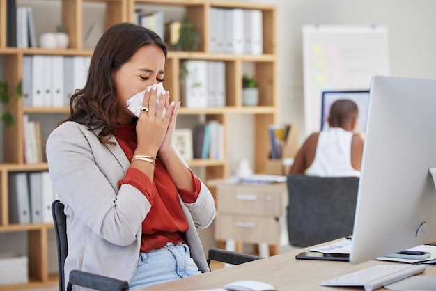 Donna d'affari malata e starnuta con influenza fredda o allergia mentre lavora in ufficio maniaco del lavoro o manager che cerca di lavorare alla scrivania con il virus della malattia covid o un cattivo equilibrio tra vita lavorativa e vita lavorativa sul posto di lavoro