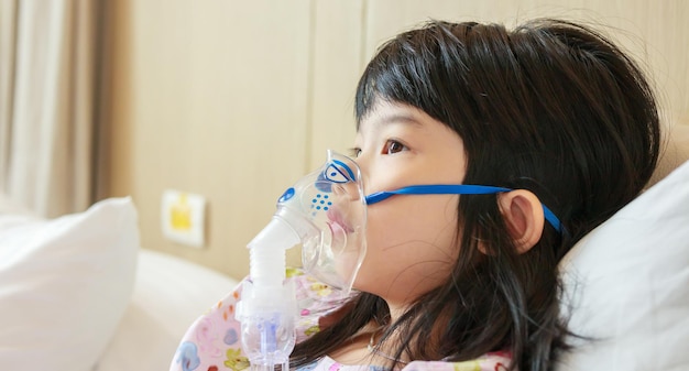 병든 작은 아시아 소녀 호흡 치료를 위해 nebulizer와 함께 흡입