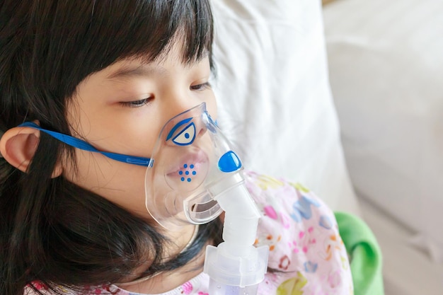 병든 작은 아시아 소녀 호흡 치료를 위해 nebulizer와 함께 흡입