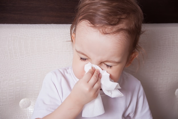 Sick little brunette girl blowing her nose