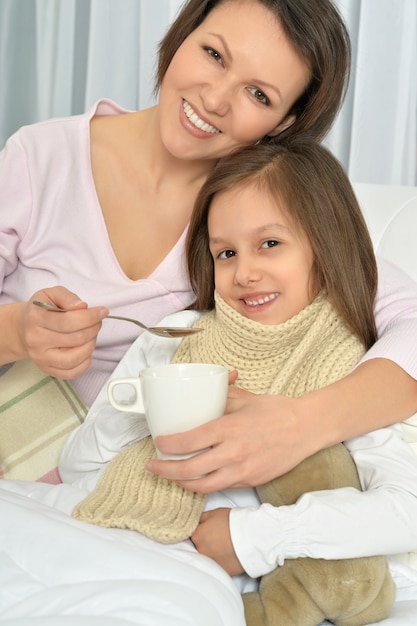 Sick little girl with mother in bed at home