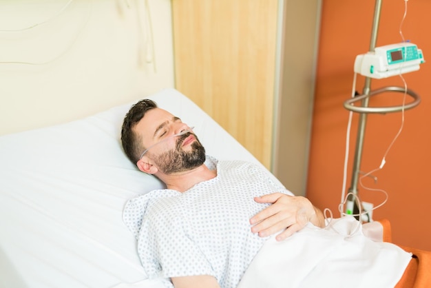병원에서 침대에 누워 있는 동안 비강 캐뉼러를 착용한 아픈 남성 환자