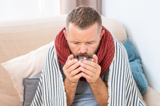 Foto uomo malato che ha la febbre, bevendo tè curativo caldo