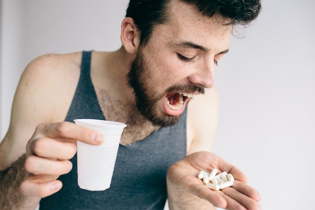 Sick man holding pills isolated on a white background