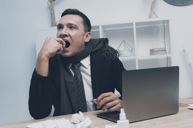 A sick man is sitting at his workplace in the office 