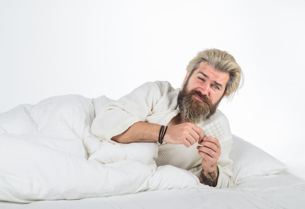 Sick man lying in bed with pills seasonal flu cold sick bearded man