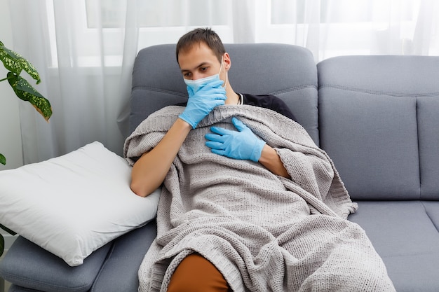 sick man in a mask and gloves lies in bed at home