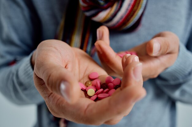 Sick man in a sweater with pills in hand health problems light
background