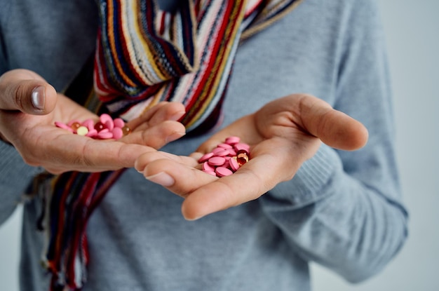 Sick man in a sweater with pills in hand health problems light\
background