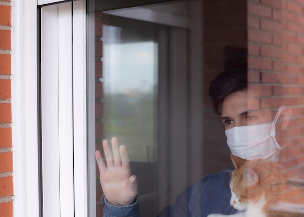 사진 왕관 바이러스가 창 밖을보고 보호 마스크를 쓰고 아픈 사람