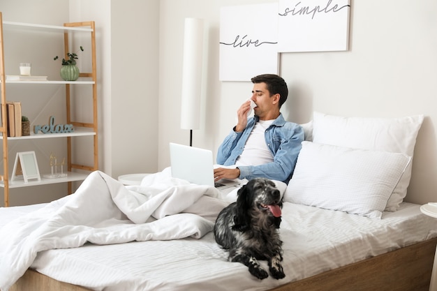 Sick man with dog working on laptop at home